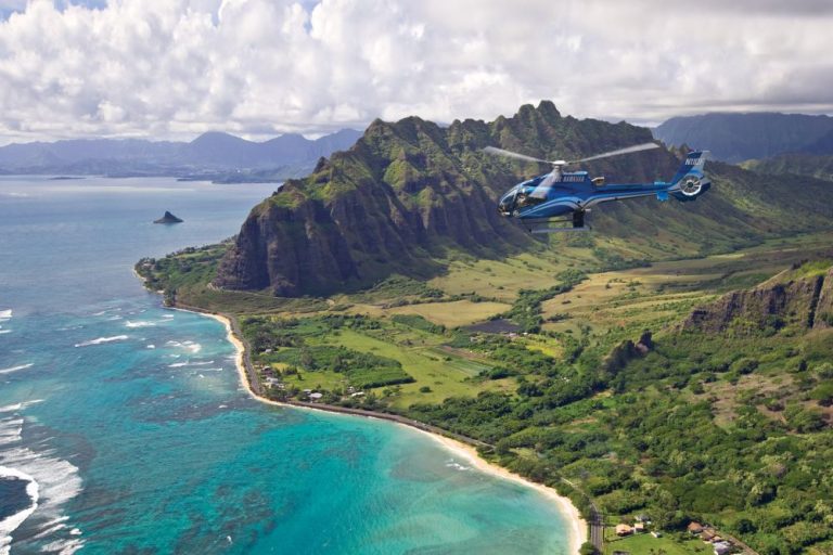 Helicopter flying past the Koolau cliffs and turquoise reefs of Oahu's windward coast
