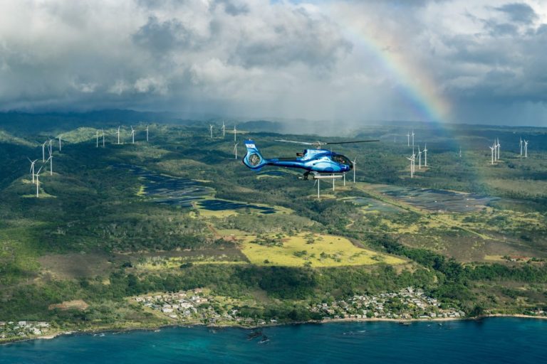 Helicopter flying beneath a rainbow over Oahu's North Shore valleys