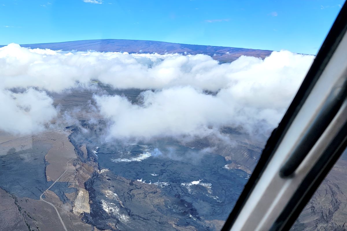The Kilauea caldera from the air through a helicopter window, steam rising through cloud