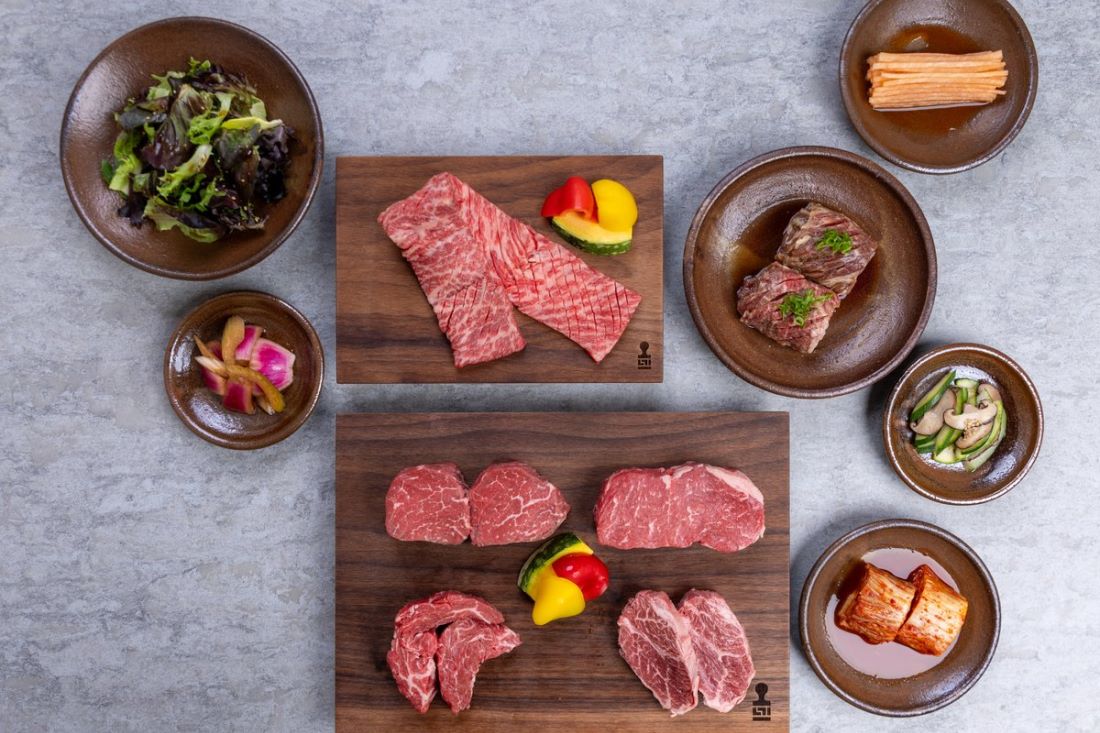 Marbled beef cuts on walnut boards with the side dishes that come with the set