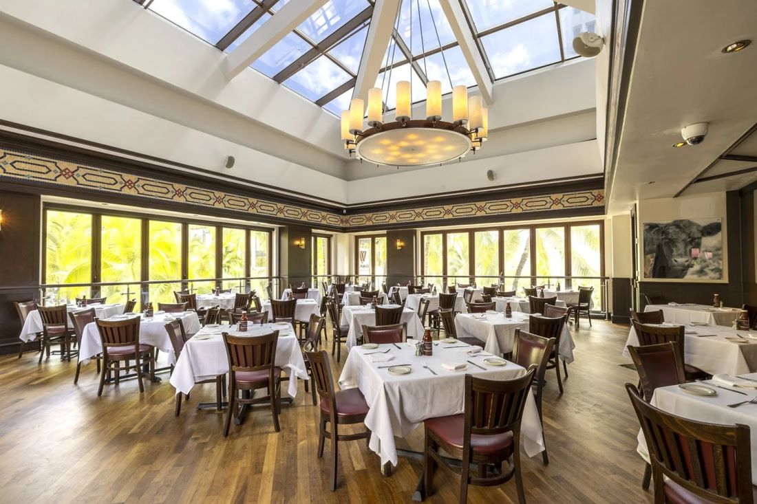 The dining room at Wolfgang’s Steakhouse Waikiki, with a skylight above white-clothed tables