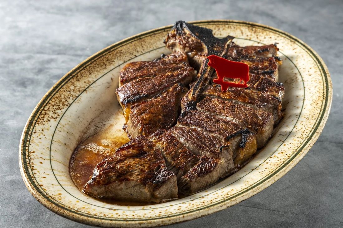 A dry-aged porterhouse, sliced and served on a hot platter