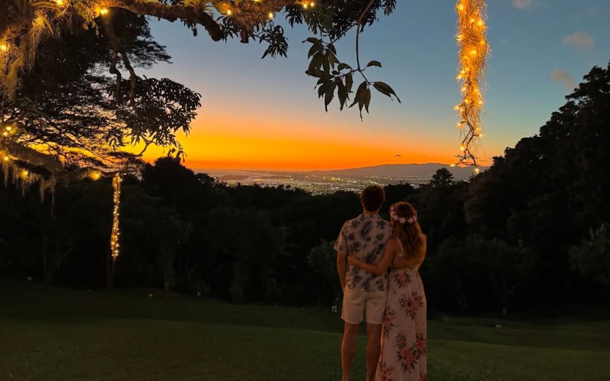 Sunset over Honolulu and the Pacific seen from the lawn at Experience Nutridge on Tantalus, with string lights in the trees