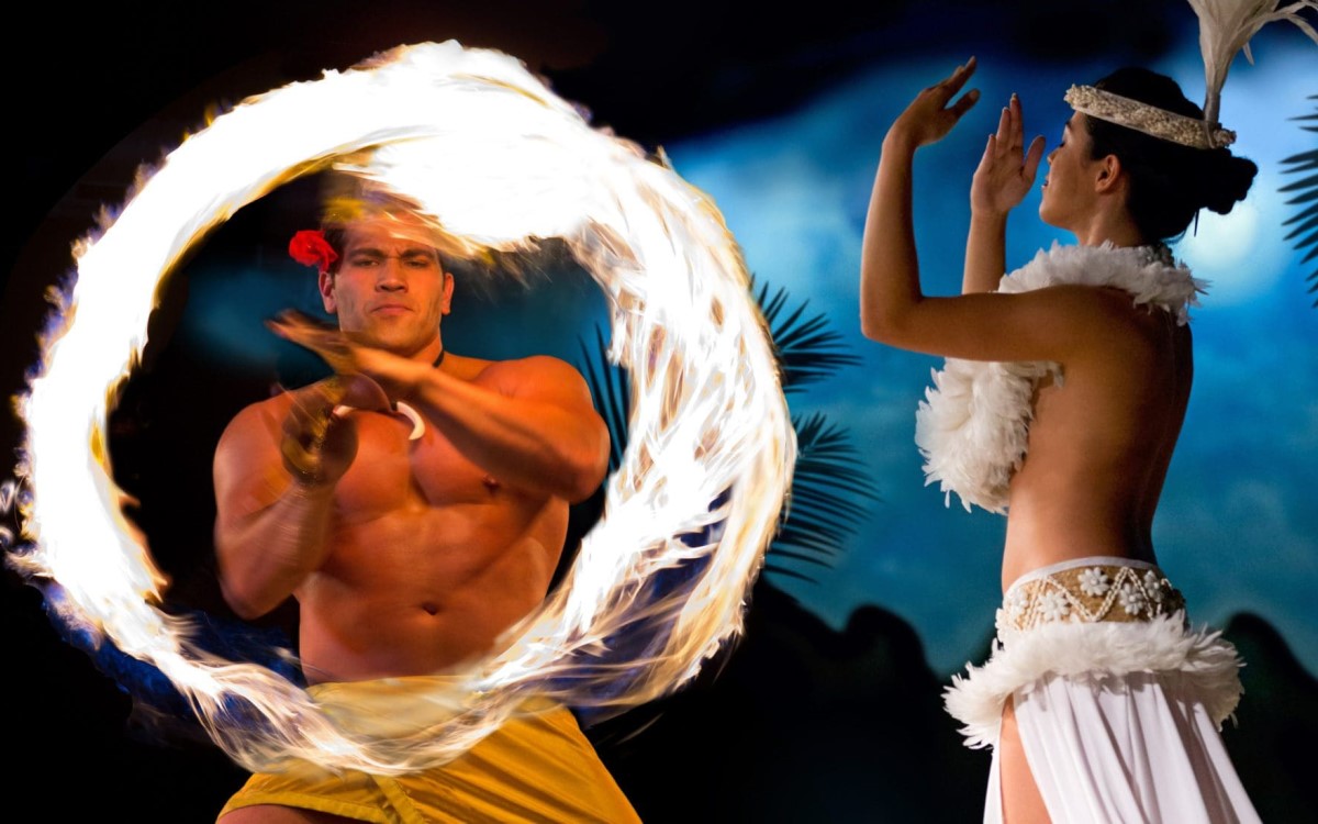 A fire knife dancer spinning a ring of flame beside a hula dancer at the Waikiki Starlight Luau