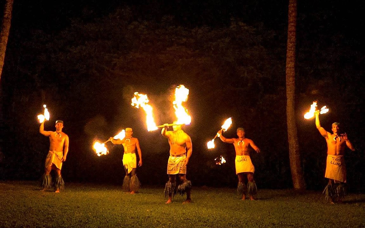 Five fire knife dancers performing among the palms after dark at Toa Luau